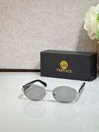 Round sunglasses with dark gray lenses, gold-tone frame, and green temple accents