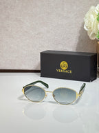 Round sunglasses with light blue lenses, gold-tone frame, and green temple accents