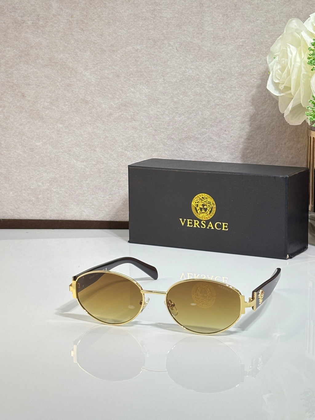 Round sunglasses with mirrored gold lenses, gold-tone frame, and black temple tips