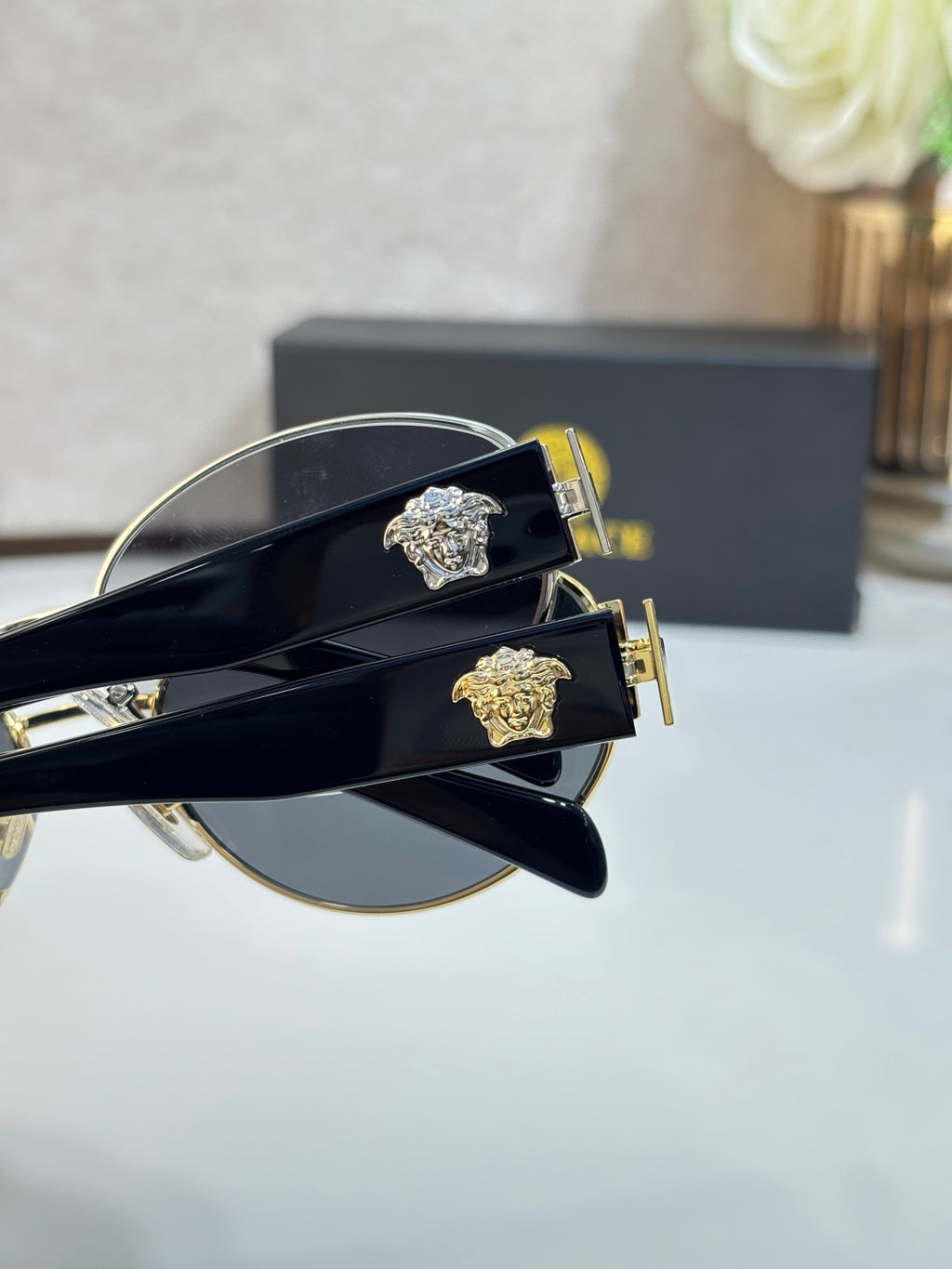 Close-up of round sunglasses with gold-tone hardware on black temple arms