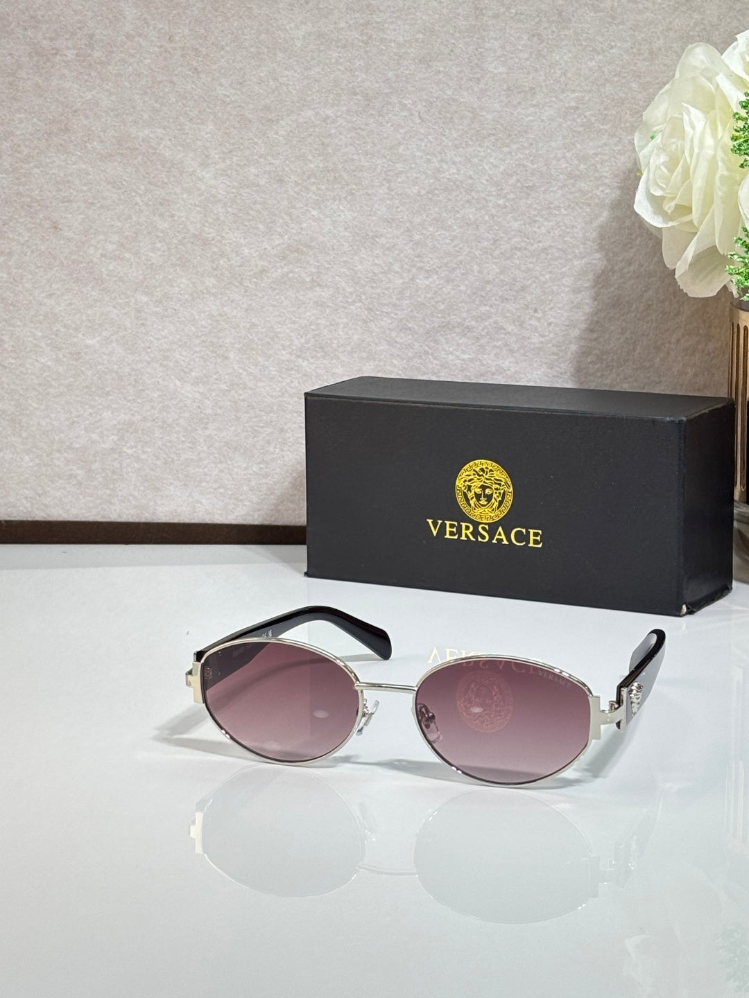 Round sunglasses with rose-tinted lenses, gold-tone frame, and black temple tips