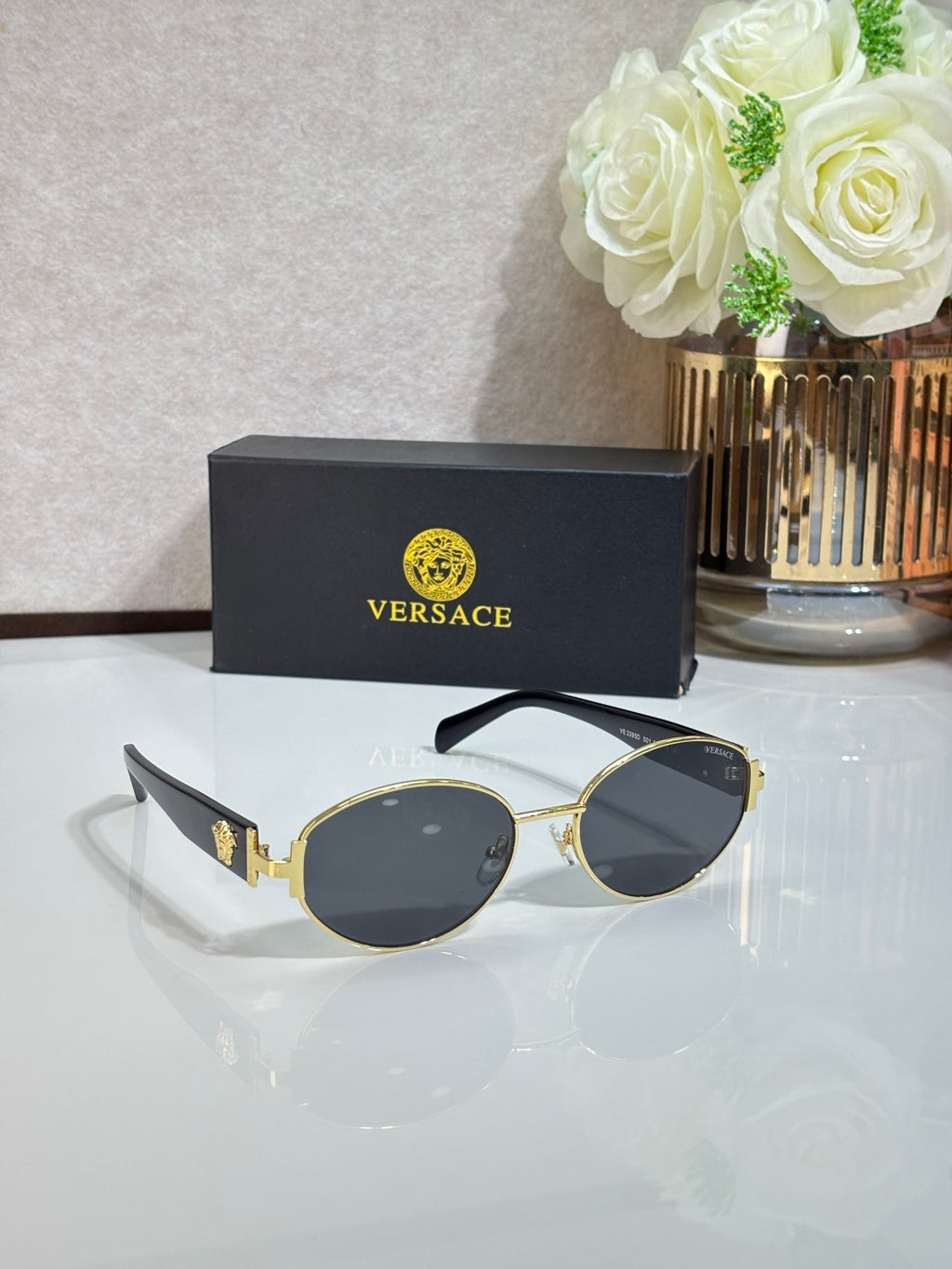 Round sunglasses with dark lenses, gold-tone frame, and black temple details