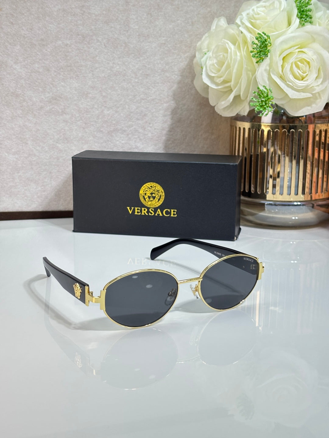 Round sunglasses with dark lenses, gold-tone frame, and black temple details