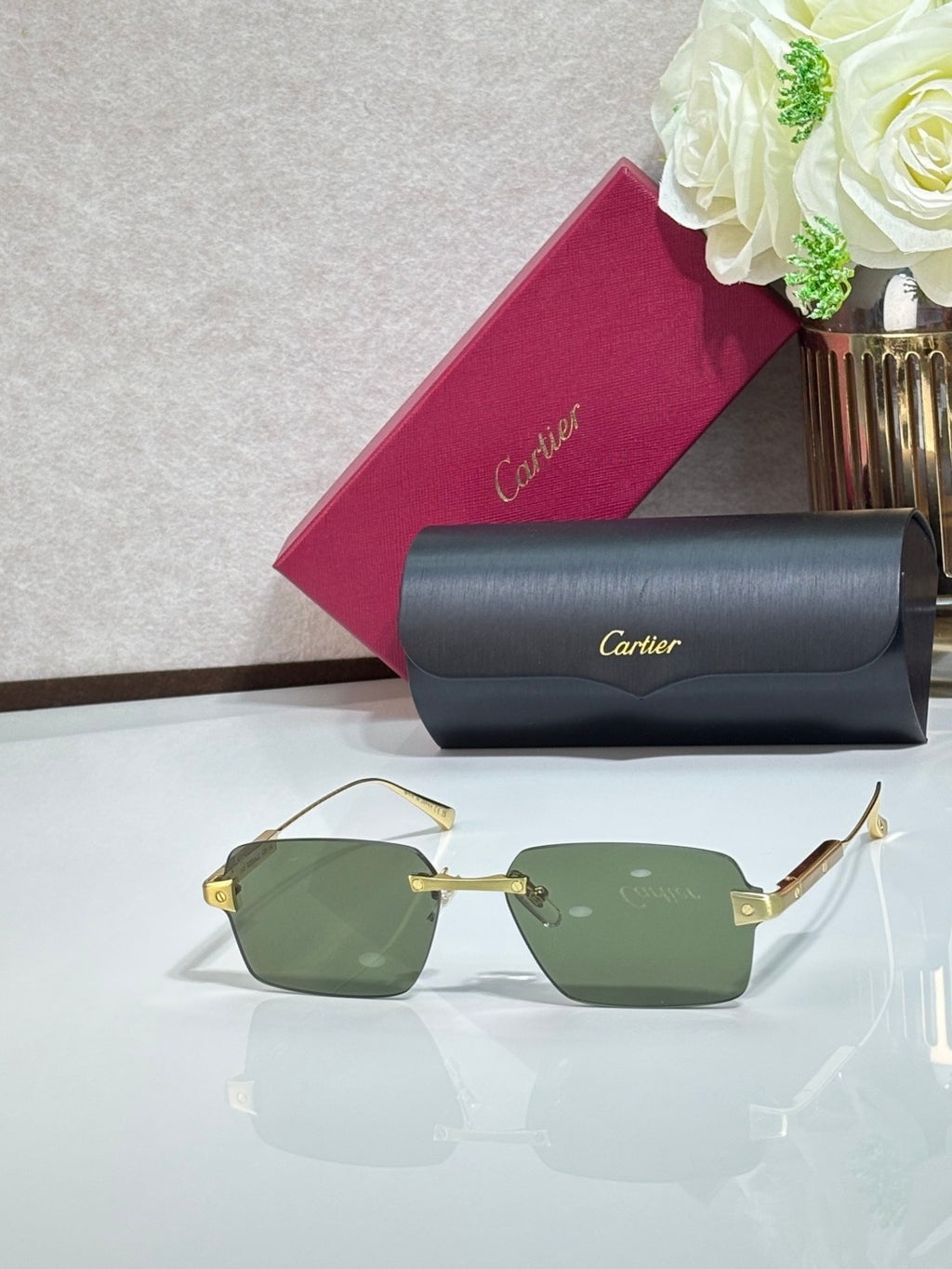 Sunglasses with green lenses, gold metal frame, and gray case