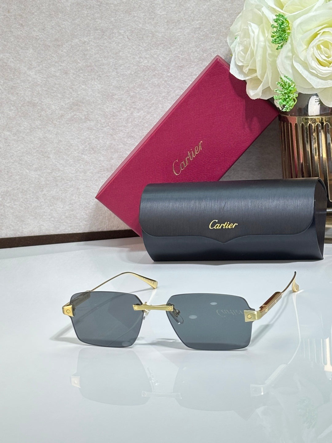 Sunglasses with gray-blue lenses, gold metal frame, and gray case