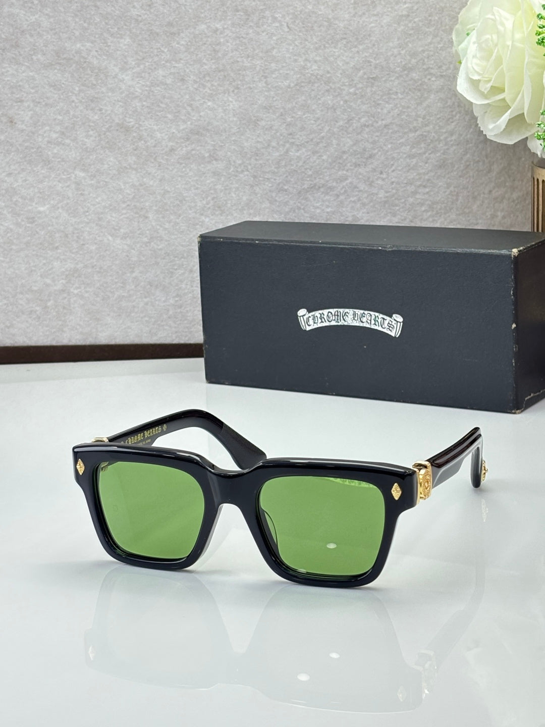 Chrome glasses with black frames and green lenses, gold-accent temples