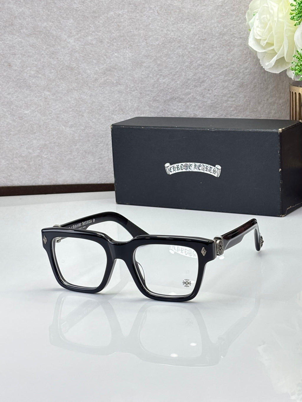 Black eyeglasses with gold-tone temple tips and clear lenses, square shape