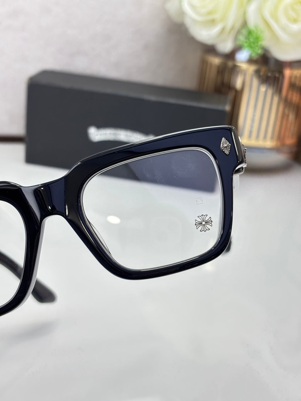 Navy eyeglasses close-up with square frames, clear lenses and metal emblem