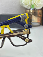 Color-block eyeglass frames with gold-tone decorative logos and clear lenses