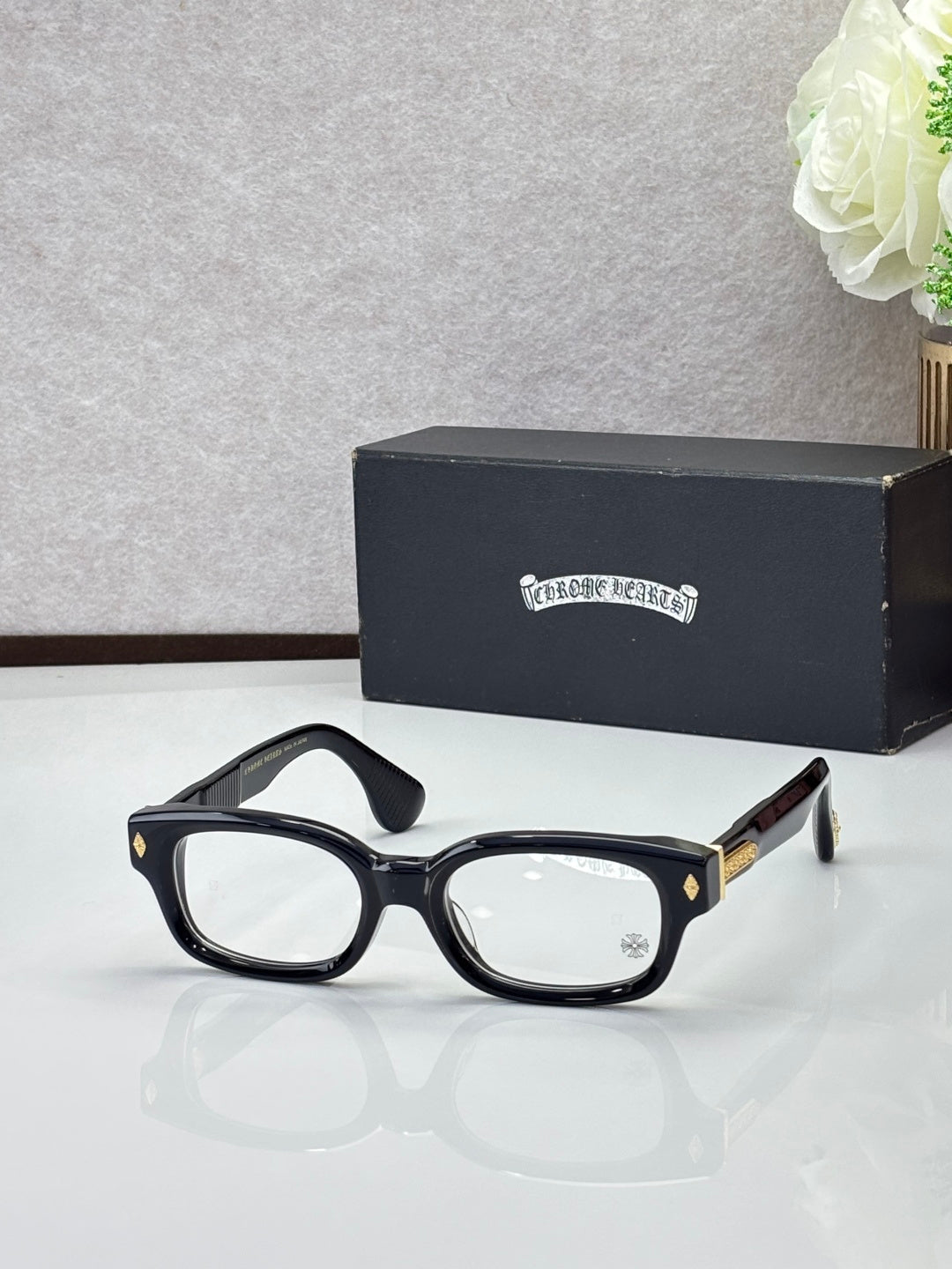 Black oval glasses with clear lenses and gold temple detail