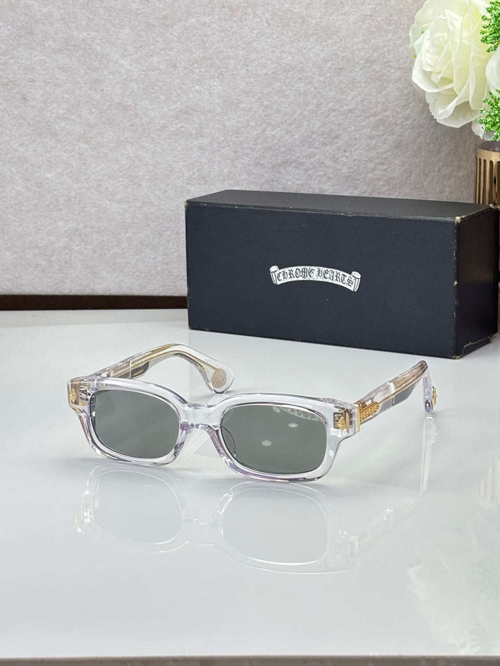 Clear oval sunglasses with gray lenses and gold-toned temple accents