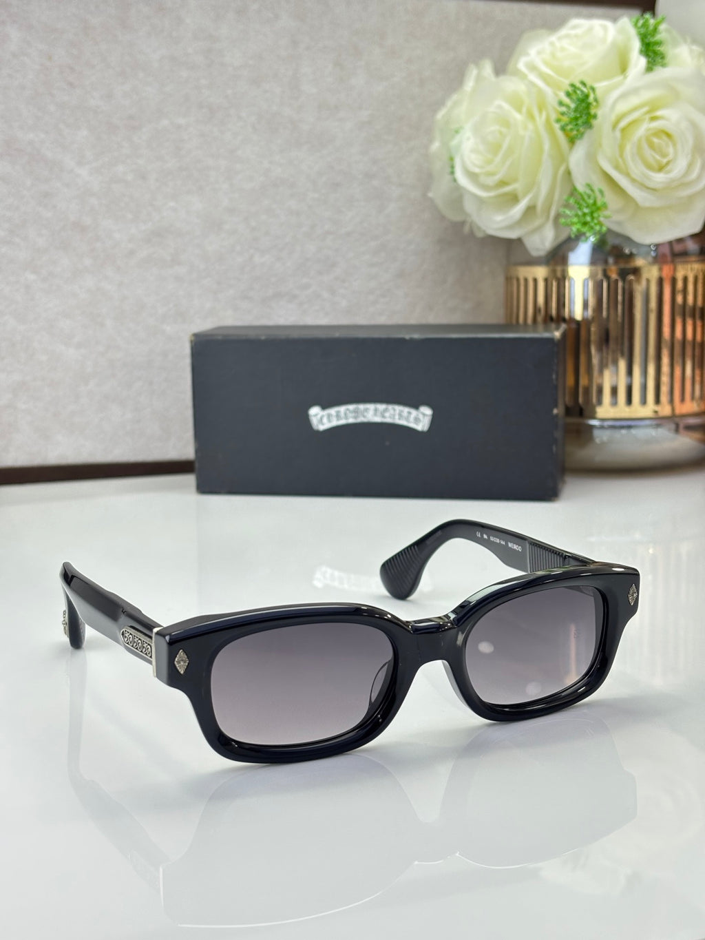 Black oval sunglasses with dark lenses and logo detail on the temples