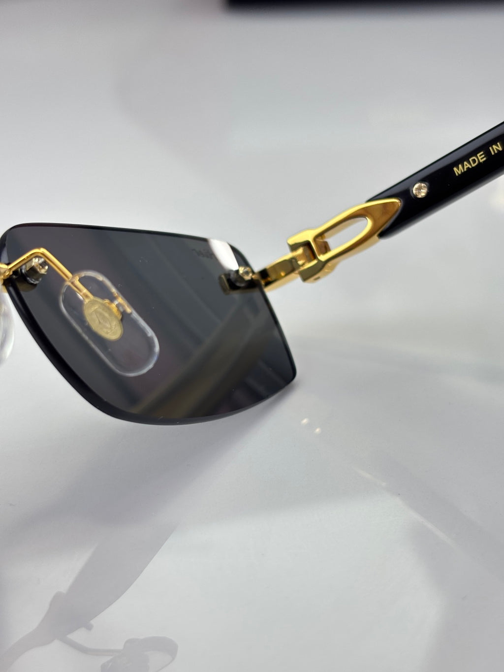 Cartier glasses close-up, dark lens with gold hinge and “Made in” marking on temple