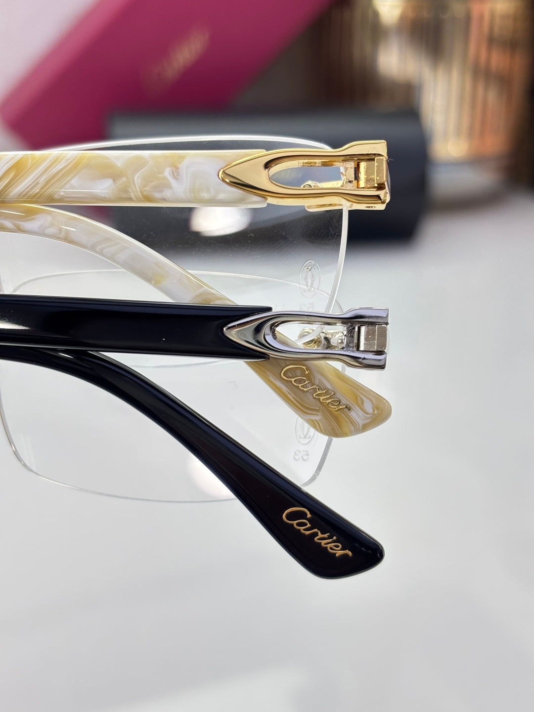 Clear eyeglasses close-up: gold-tone temple hinge with patterned temple arm.