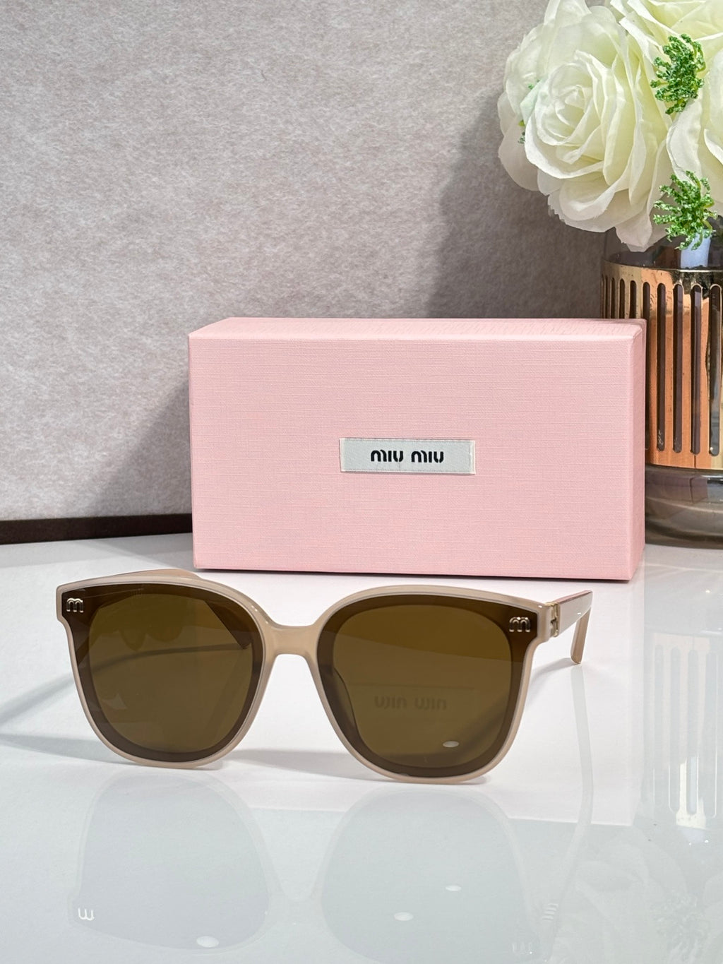 Light brown round sunglasses with dark green lenses and gold side emblems