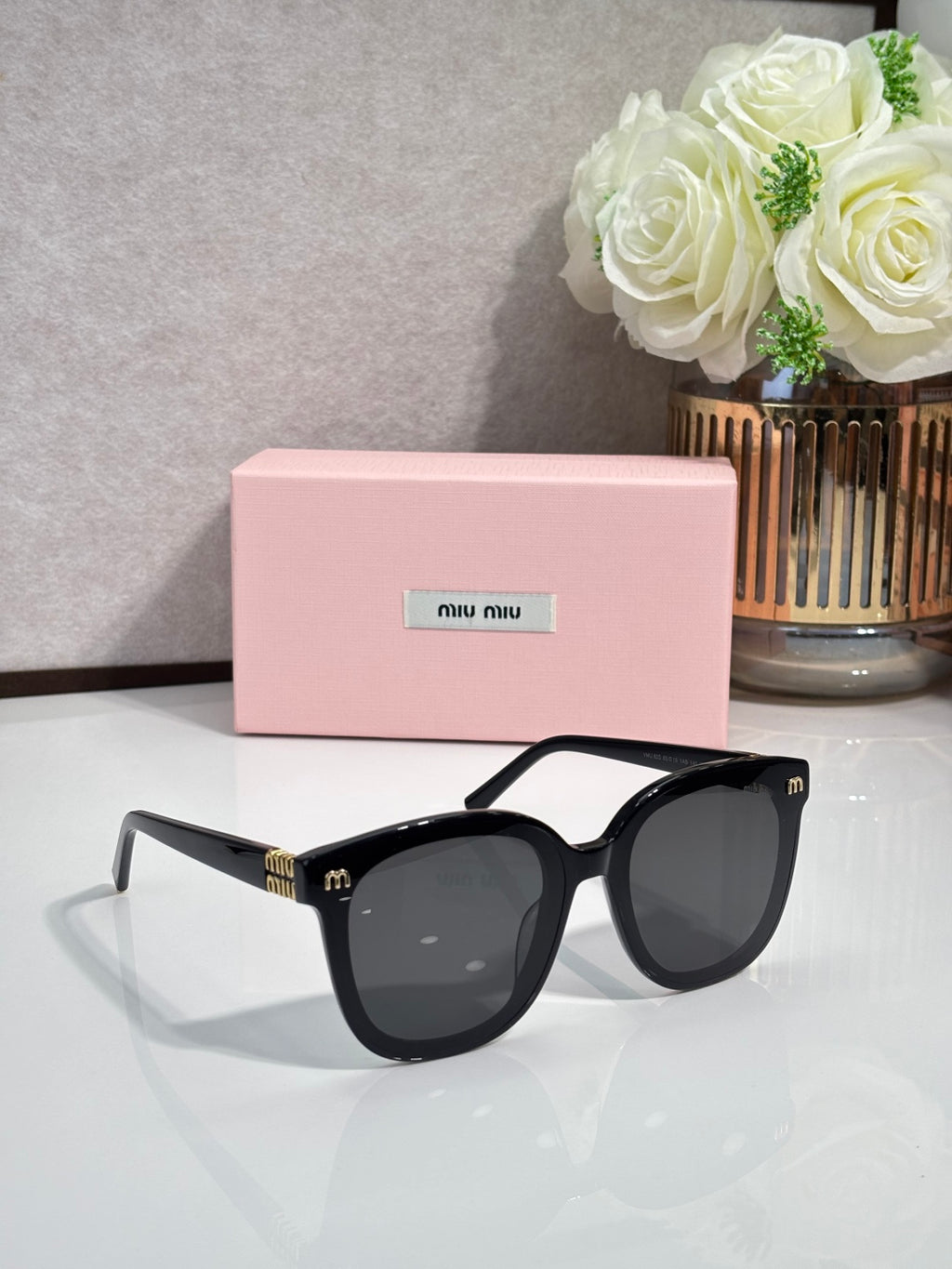 Black oversized round sunglasses with dark lenses and gold logo on temples