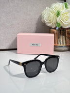 Black oversized round sunglasses with dark lenses and gold logo on temples
