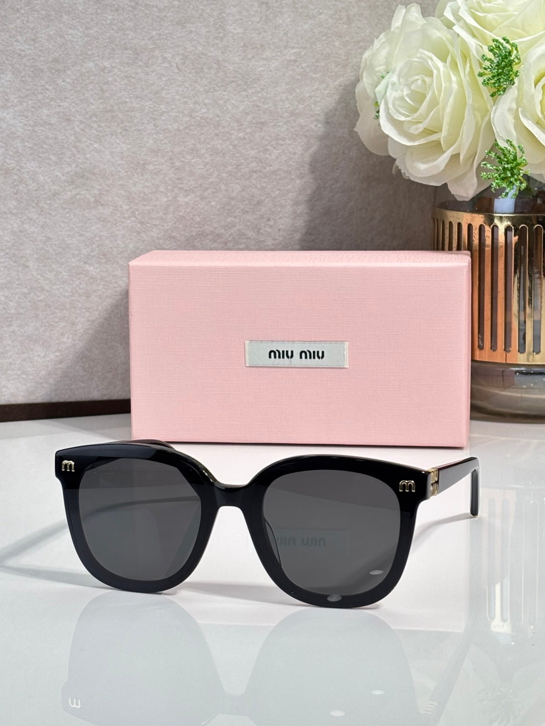 Black round sunglasses with dark gray lenses and gold logo accents on temples