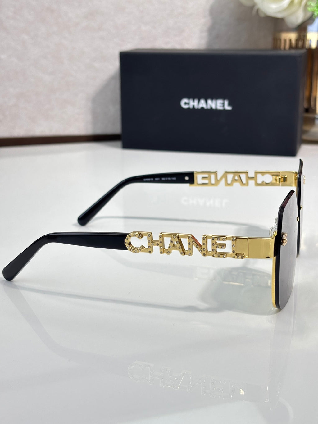 Chanel sunglasses side view with black frame and gold-tone temple lettering