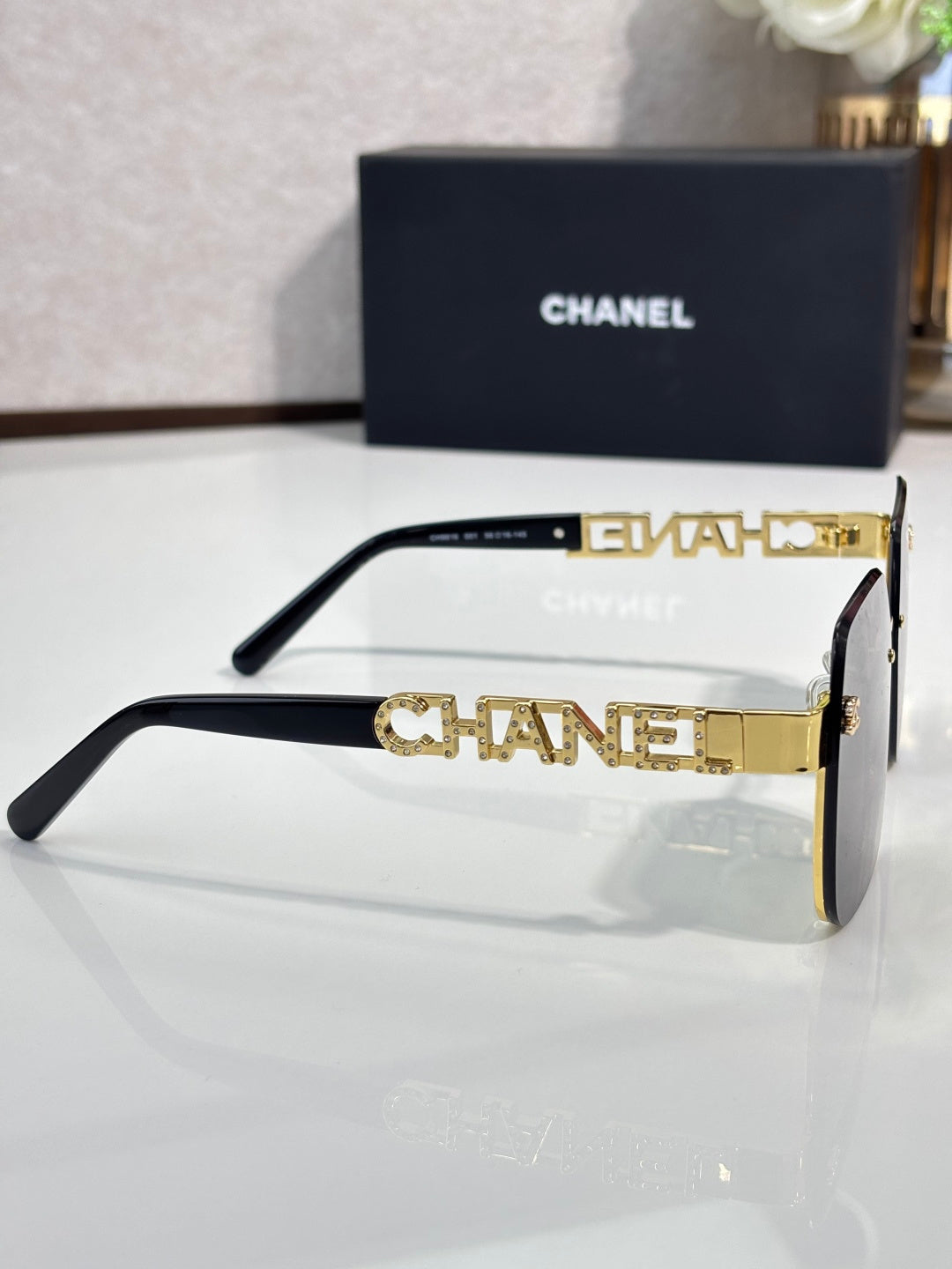 Chanel sunglasses side view with black frame and gold-tone temple lettering