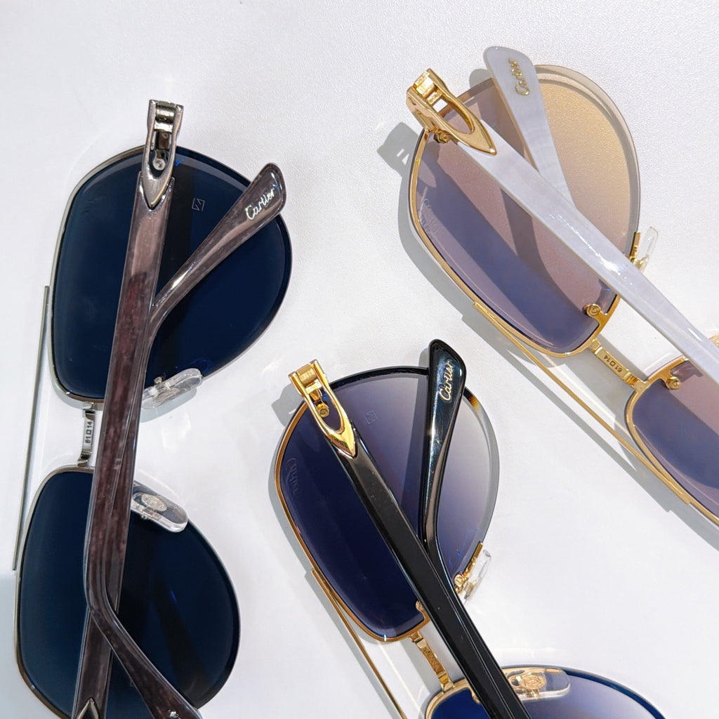 Sunglasses with gold accents and dark blue tinted lenses, overlapping angles