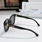 Sunglasses side view with glossy black frame and dark tinted lenses, gold logo detail
