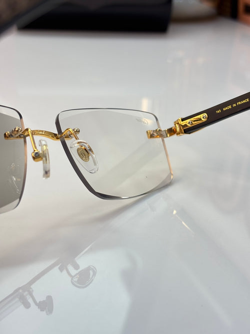 Metal eyeglasses with clear lenses, gold-tone bridge, and dark temple tips