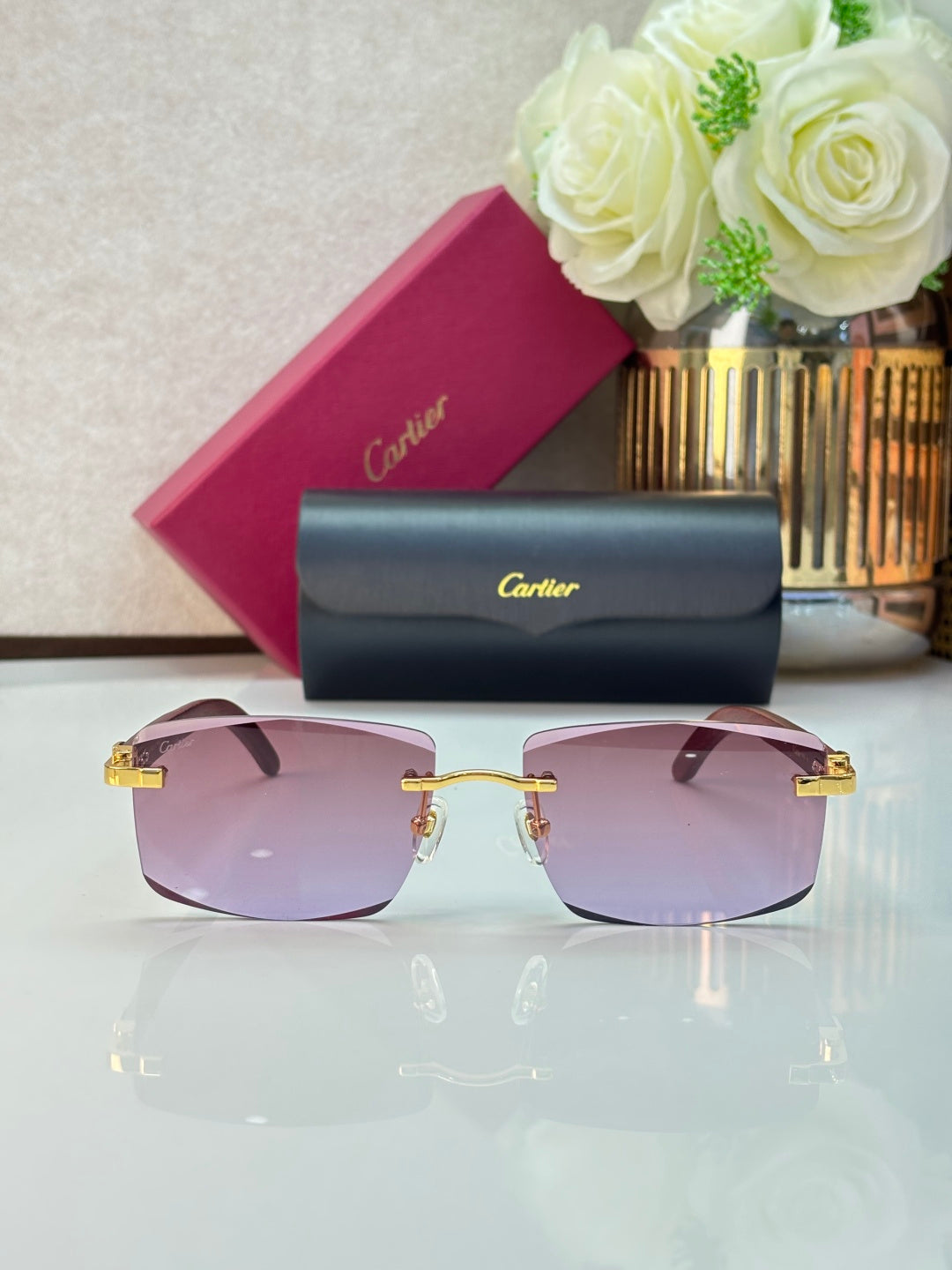 Square eyeglasses with pink-tinted lenses, dark frames, and gold-tone hinges