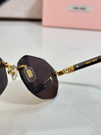 MiuMiu dark round sunglasses close-up with gold bridge and emblem