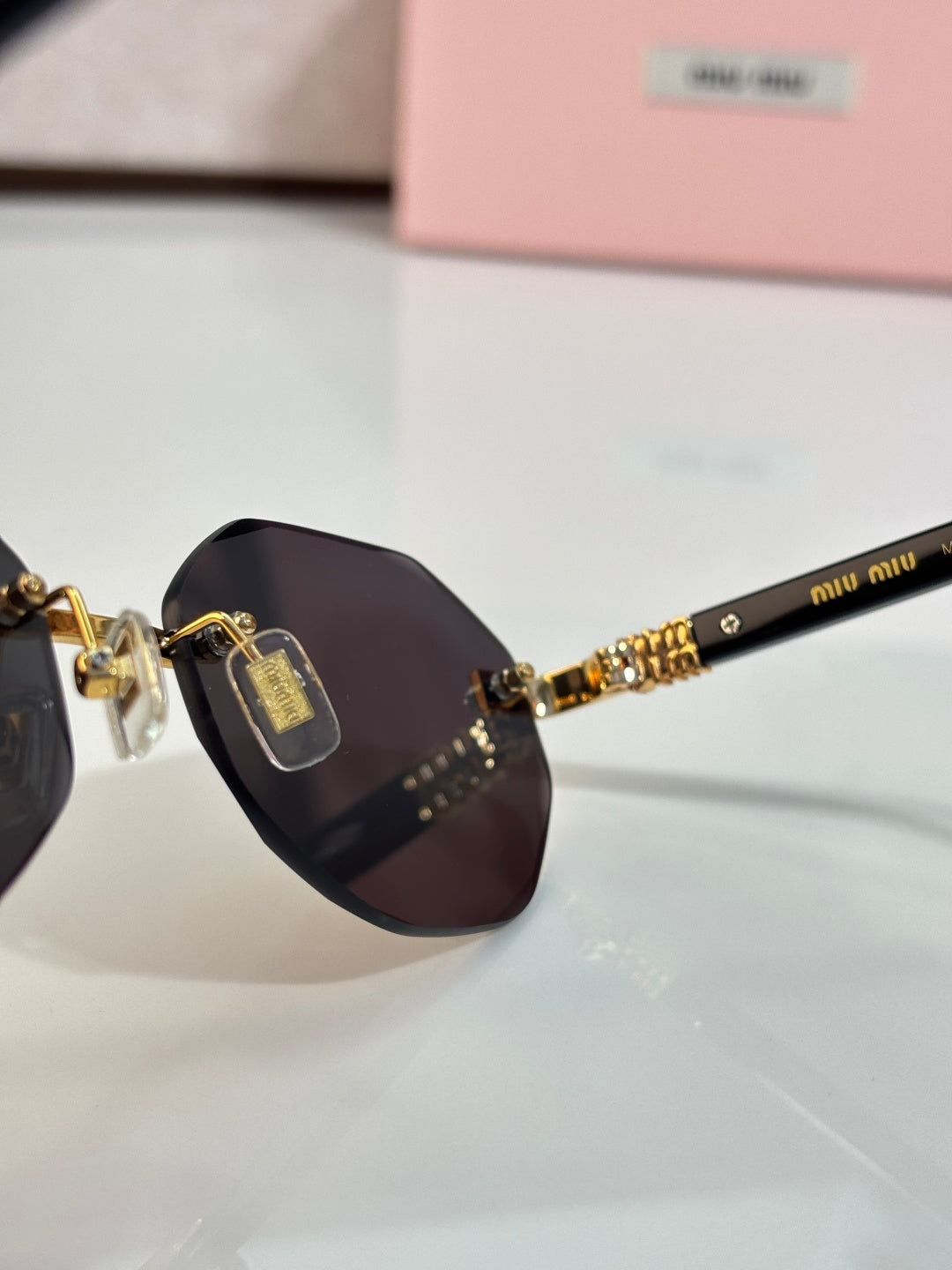 MiuMiu dark round sunglasses close-up with gold bridge and emblem