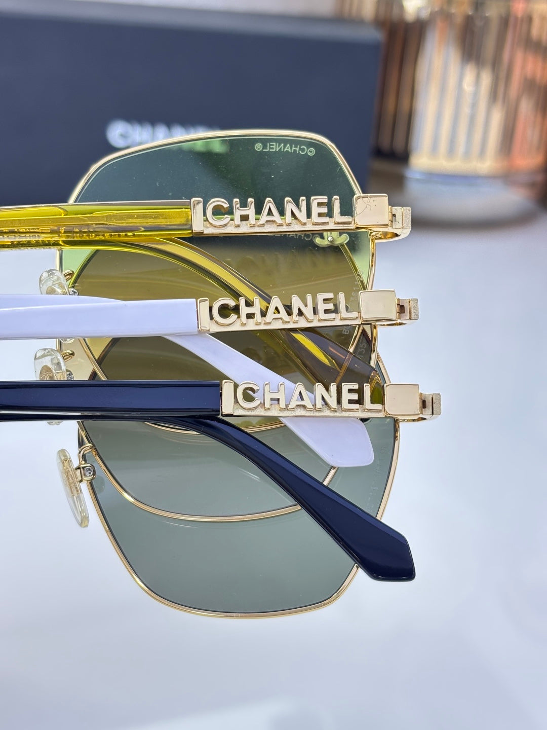 Chanel sunglasses close-up with navy temples and gold frame; gray lens