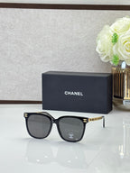 Chanel sunglasses with black frames, dark lenses, and gold logo details on the temples