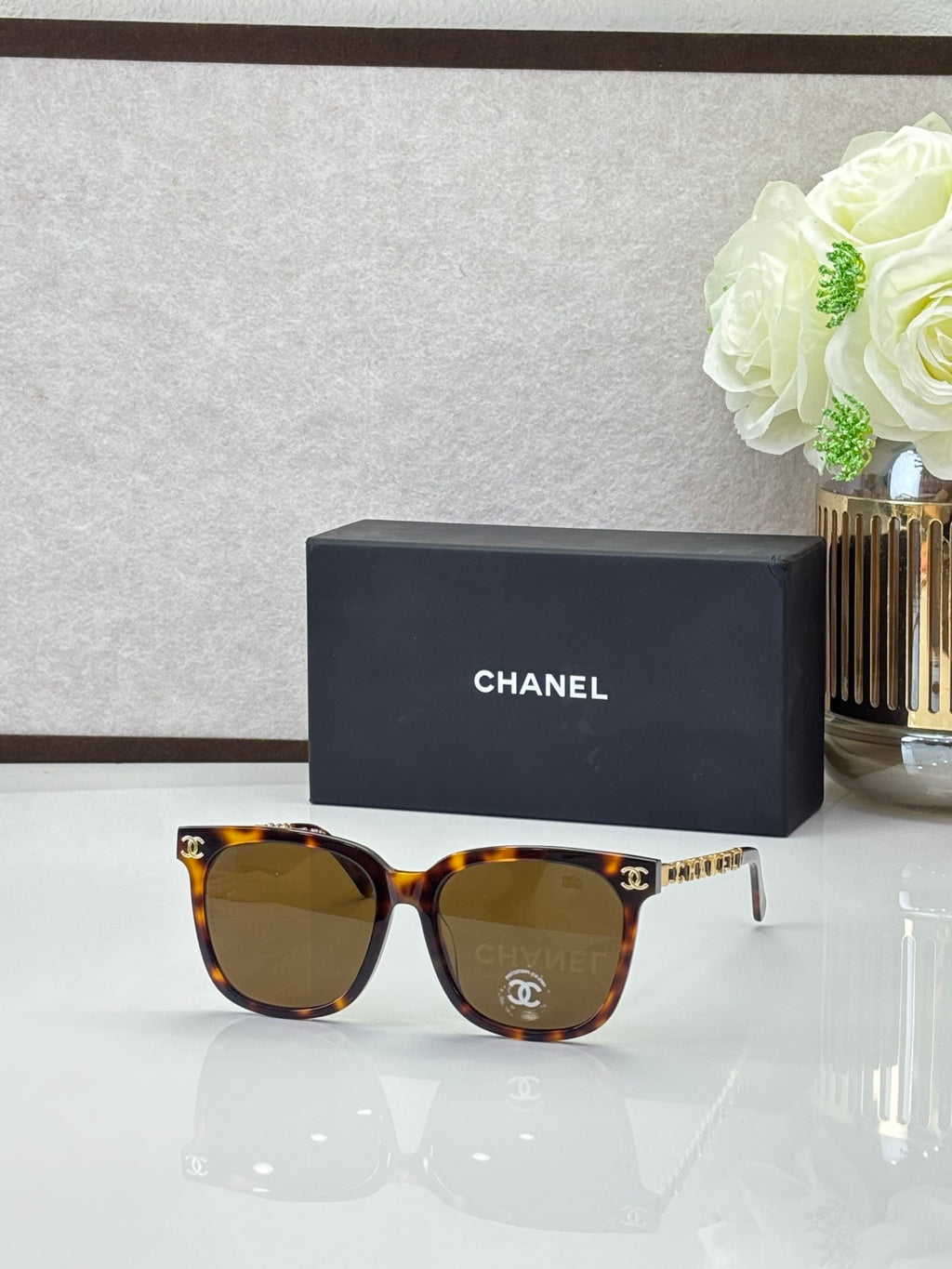 Chanel sunglasses with warm tortoiseshell frames, dark lenses, and gold logo details on the temples
