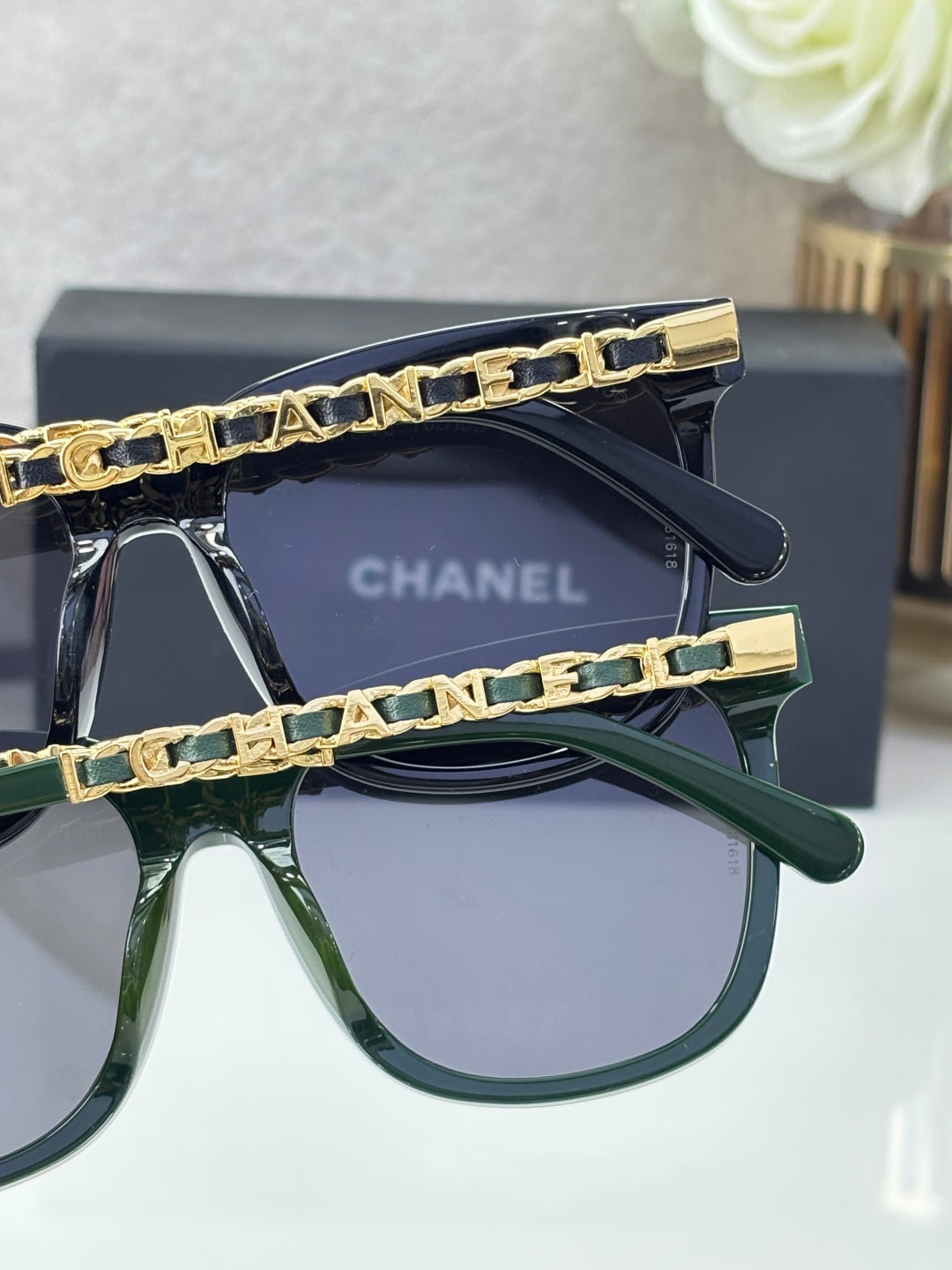 Chanel sunglasses close-up: two frames with gold chain temples, dark blue and green lenses
