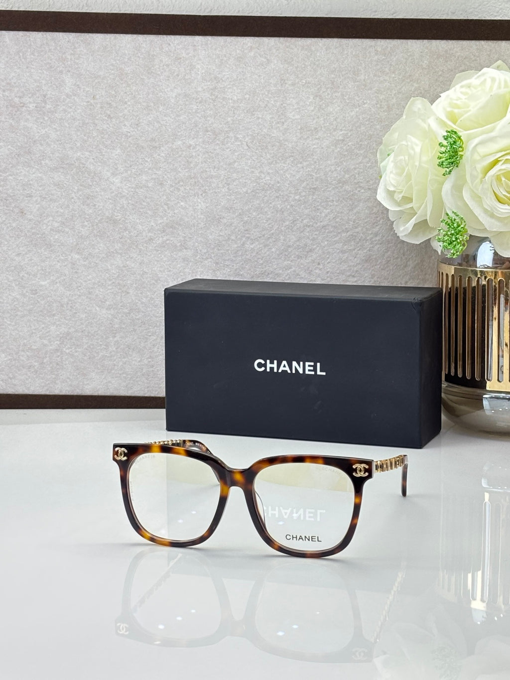 Chanel sunglasses with light tortoiseshell frames and clear lenses, with gold logo details