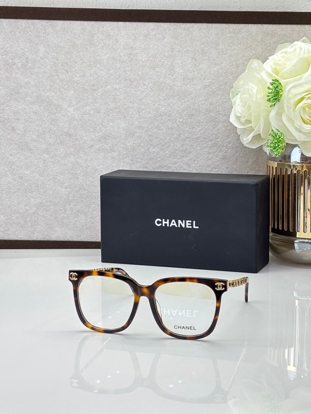 Chanel sunglasses with light tortoiseshell frames and clear lenses, with gold logo details