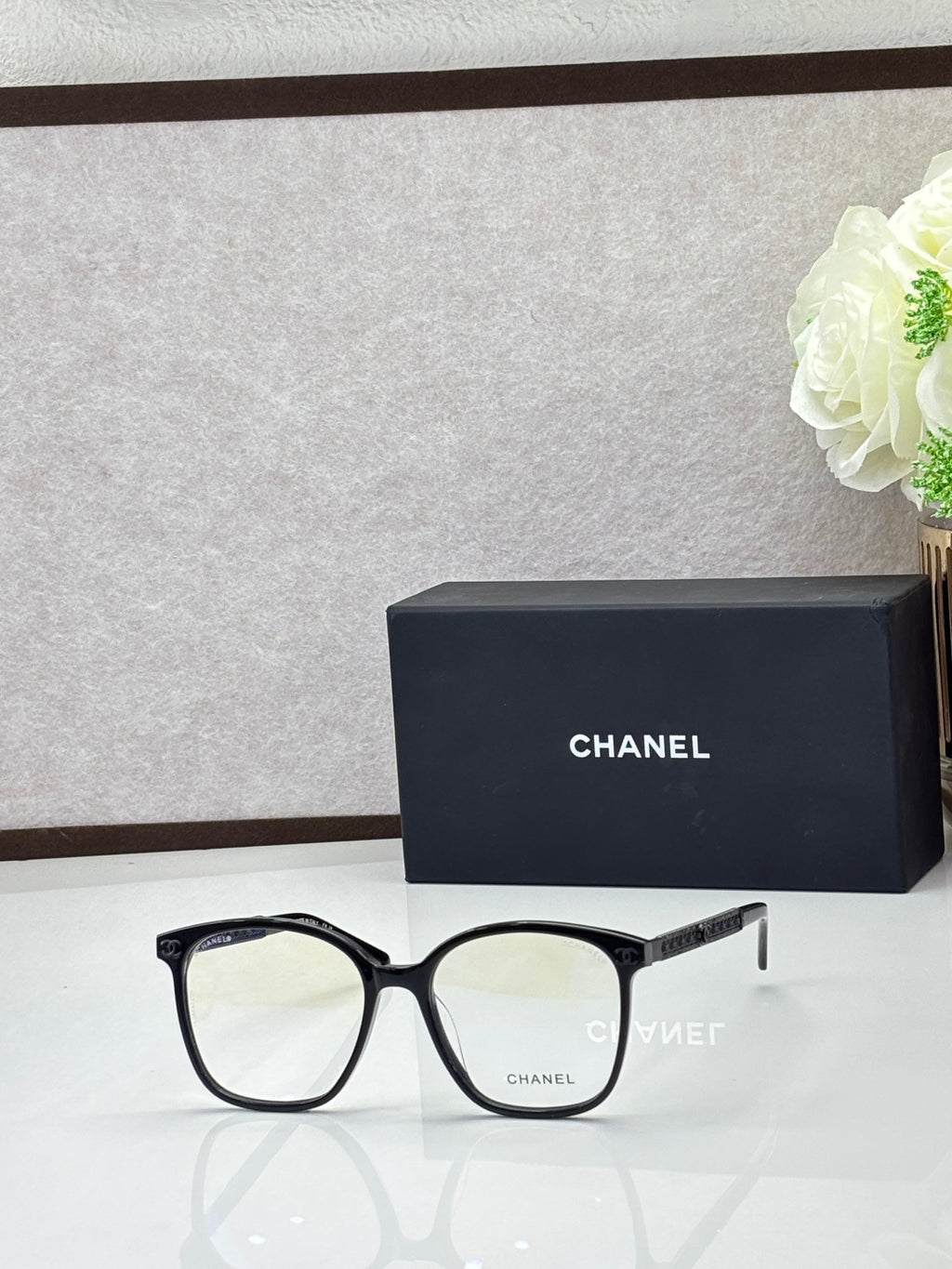 Chanel eyeglasses with black square frames and light lenses, silver-tone logo temples