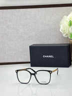 Chanel eyeglasses with black square frames and clear lenses, gold-tone logo temples