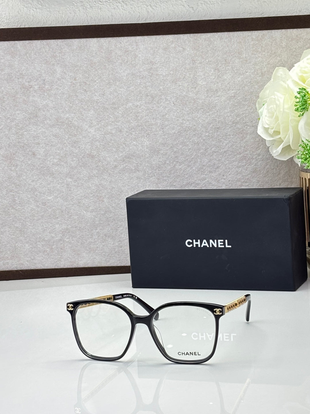 Chanel eyeglasses with black square frames and clear lenses, gold-tone logo temples