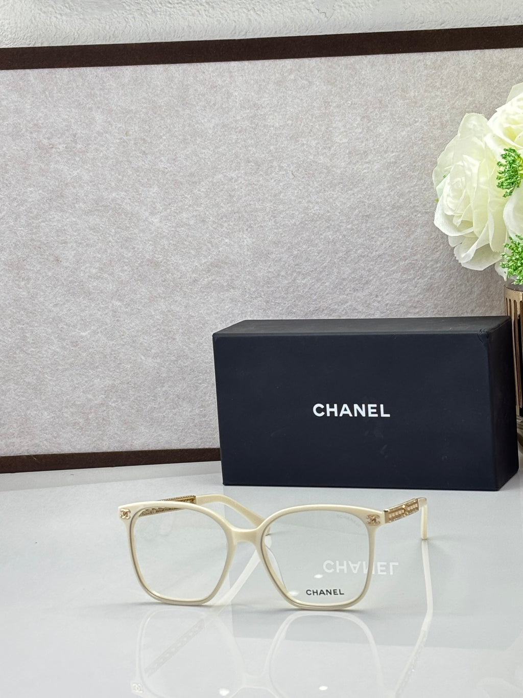 Chanel eyeglasses with off-white square frames and clear lenses, gold-tone logo temples