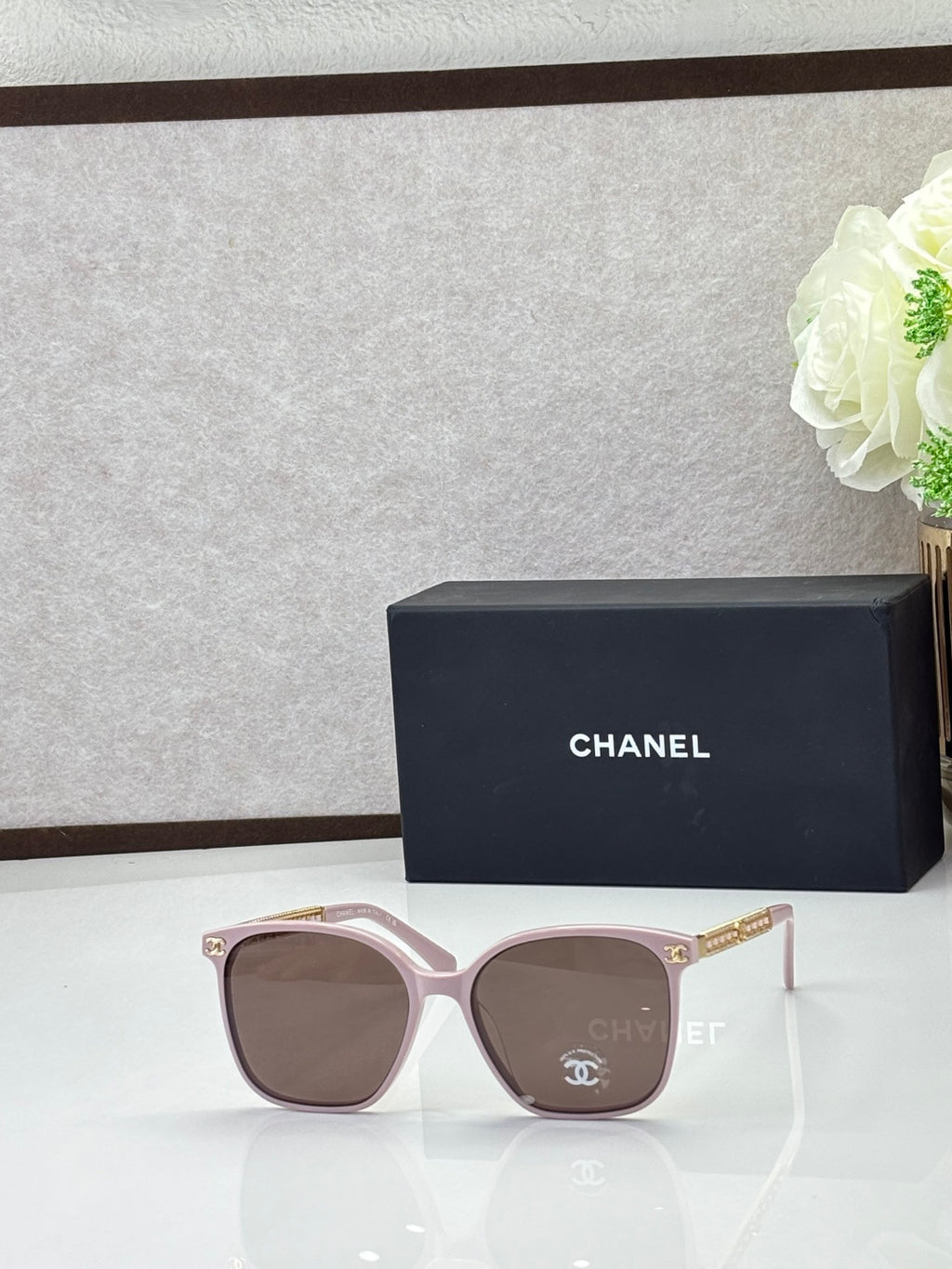 Chanel eyeglasses with light pink square frames and tinted lenses, logo temples