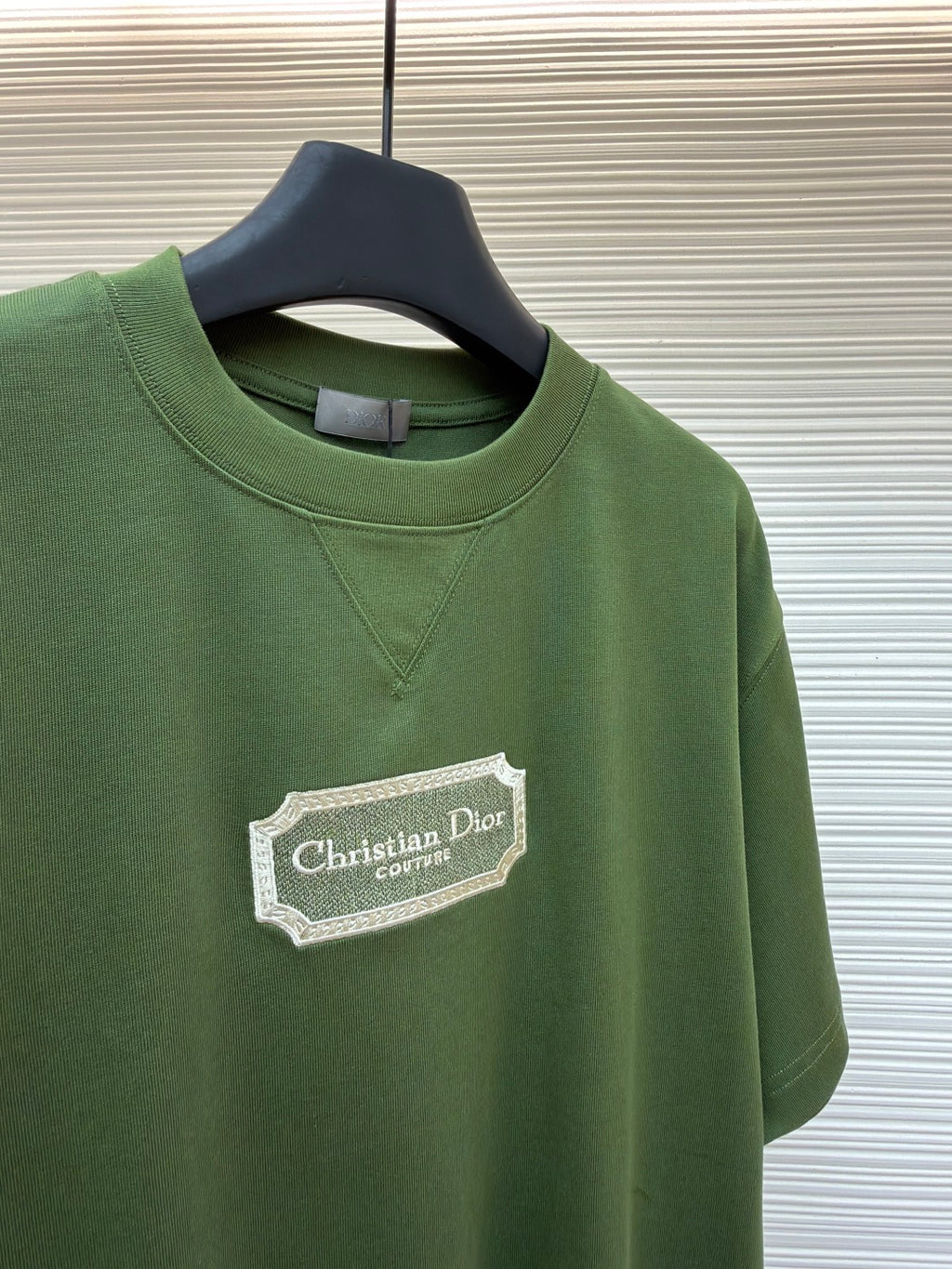Green T-shirt chest logo and crew neck on hanger