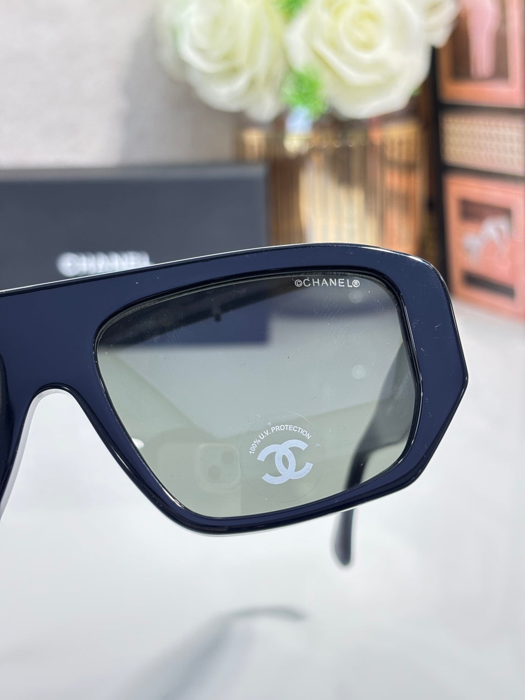 Chanel glasses with navy frame and dark tinted lenses, close-up on temple