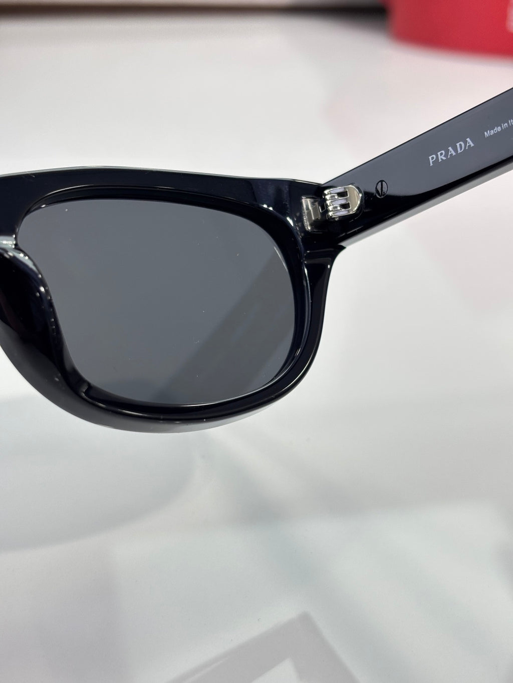 Prada sunglasses close-up of dark lens and bridge in glossy black frame