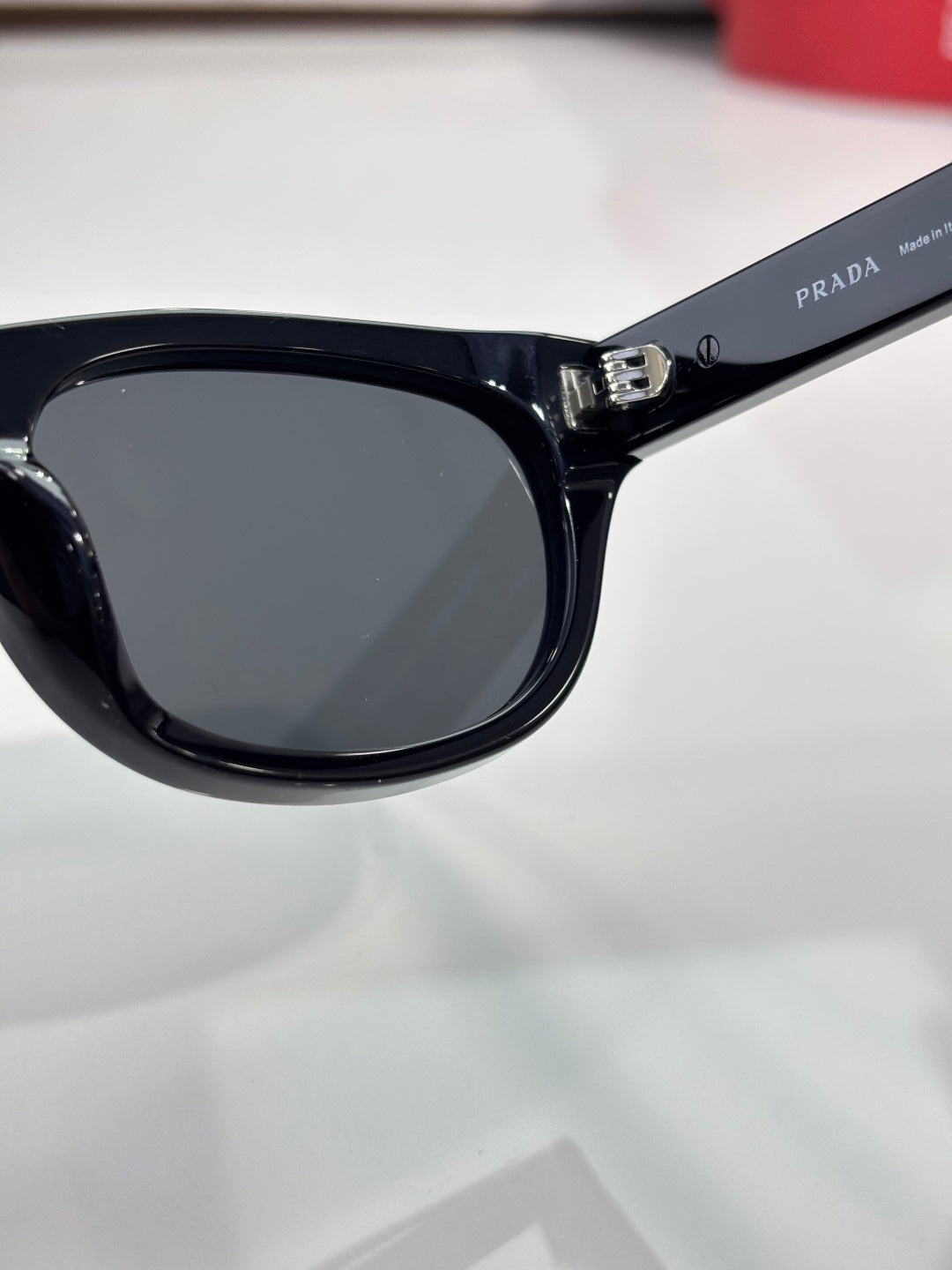 Prada sunglasses close-up of dark lens and bridge in glossy black frame
