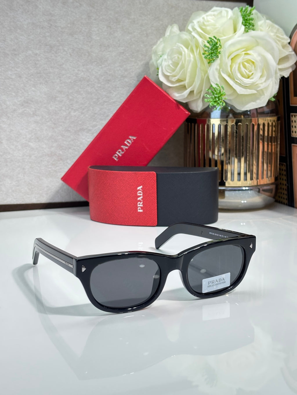 Prada sunglasses with black frame and dark lenses, side angle with gold accents
