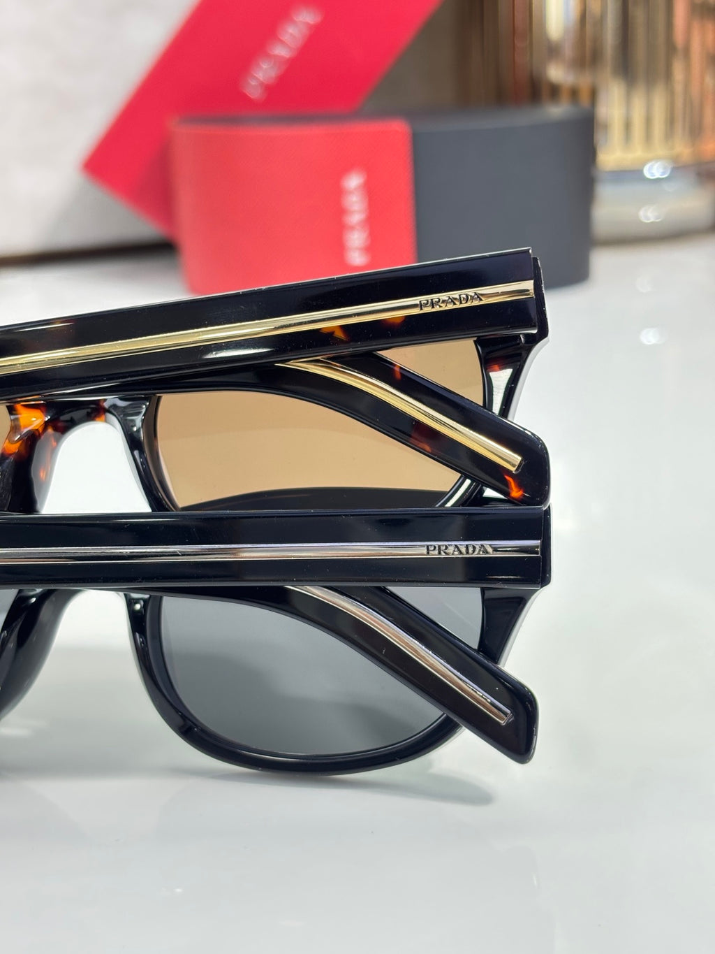 Prada sunglasses with black frame and gold-trim temples, side view detail