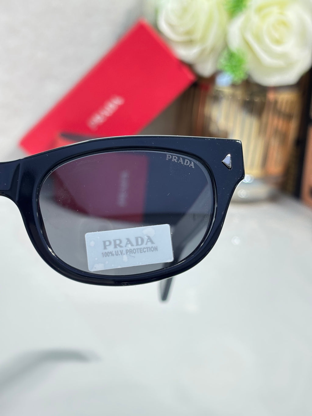 Prada sunglasses close-up of dark lens in glossy black frame with temple logo