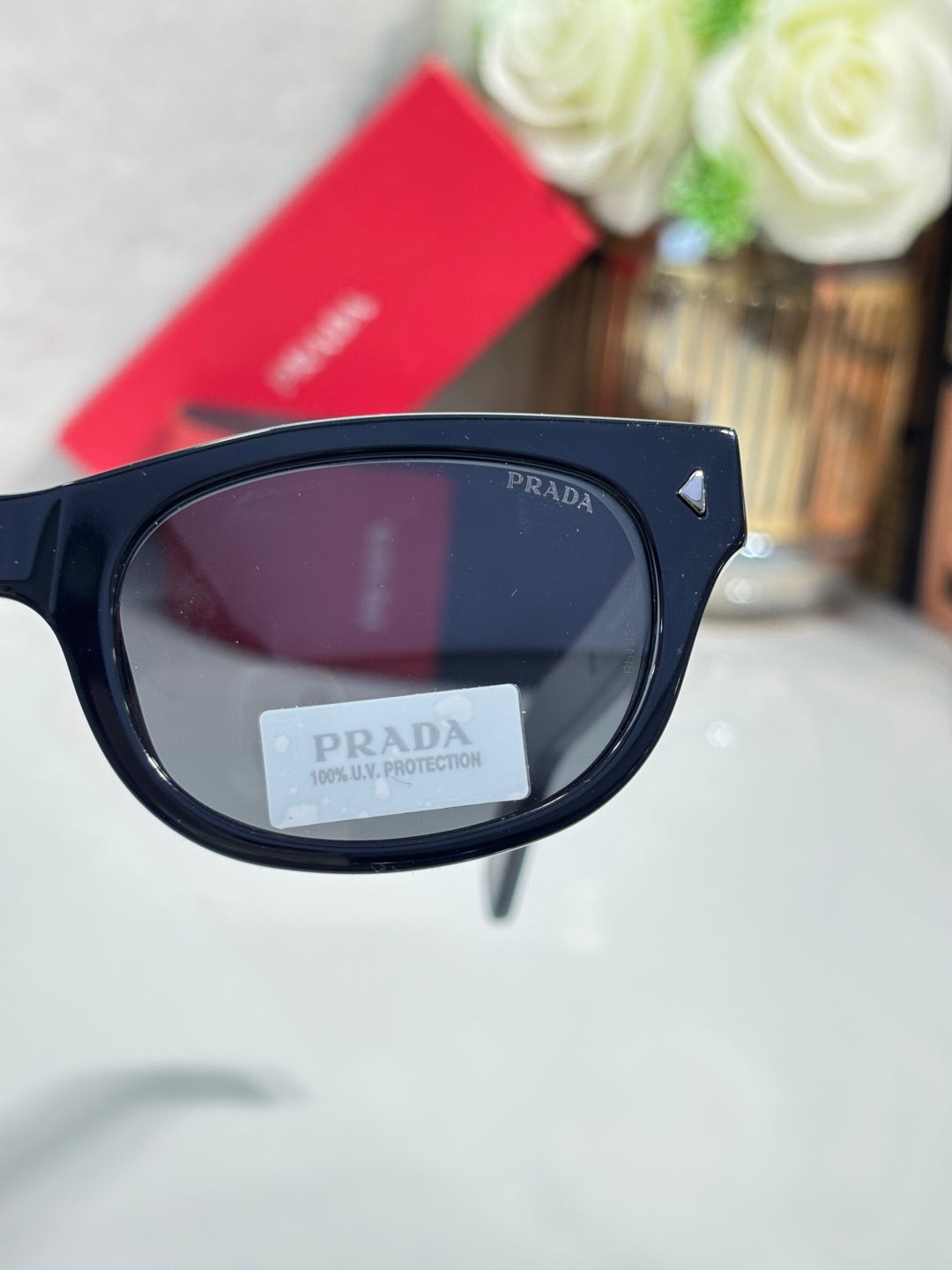Prada sunglasses close-up of dark lens in glossy black frame with temple logo