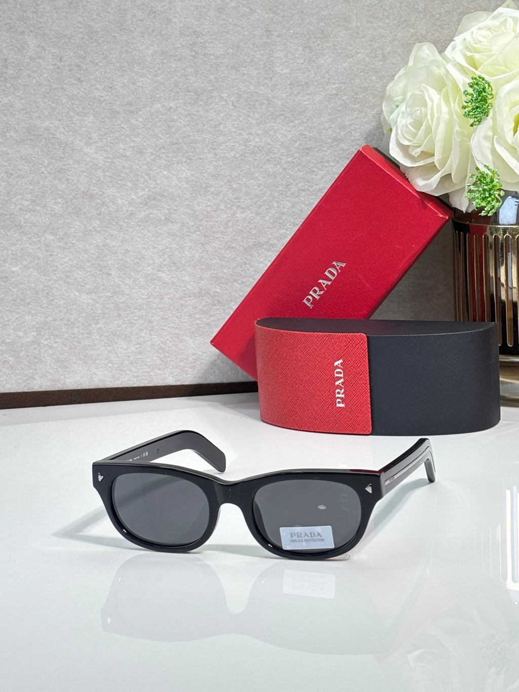 Prada sunglasses with black frame and dark tinted lenses, rounded rectangle shape